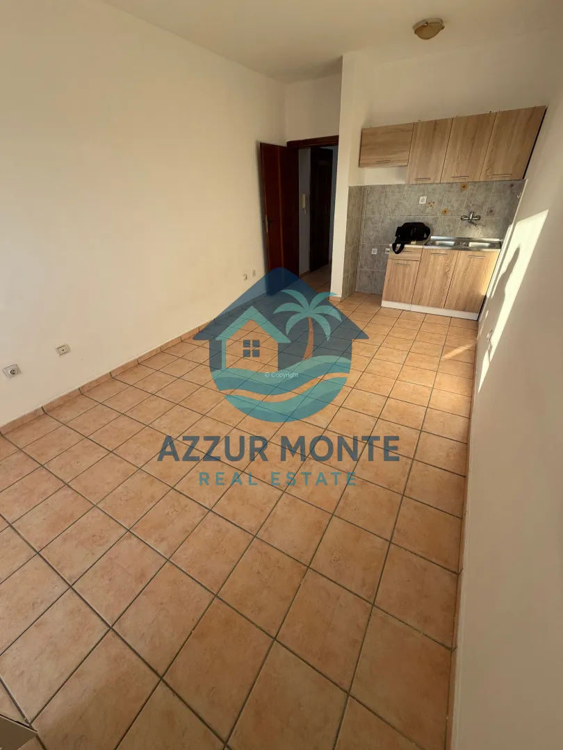 Empty room with a small kitchen and ceramic tile flooring.