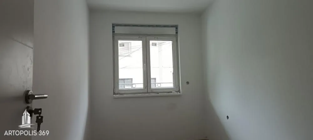 Prazna neopremljena prostorija sa belim zidovima i prozorom.
