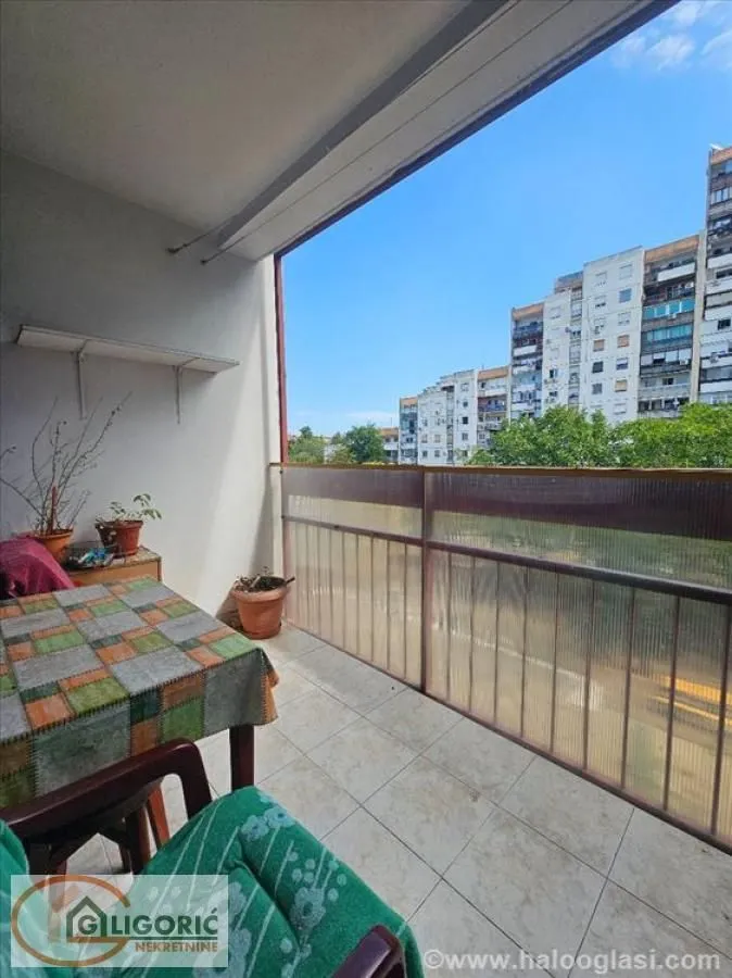 Covered balcony space with a table, chairs, and a view of surrounding buildings.