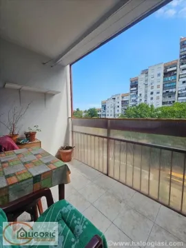 Covered balcony space with a table, chairs, and a view of surrounding buildings. - image 12