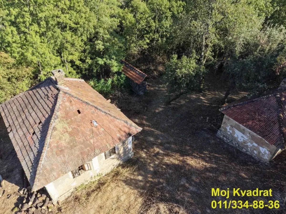 Pogled iz vazduha na stare kamene kuće okružene šumom.