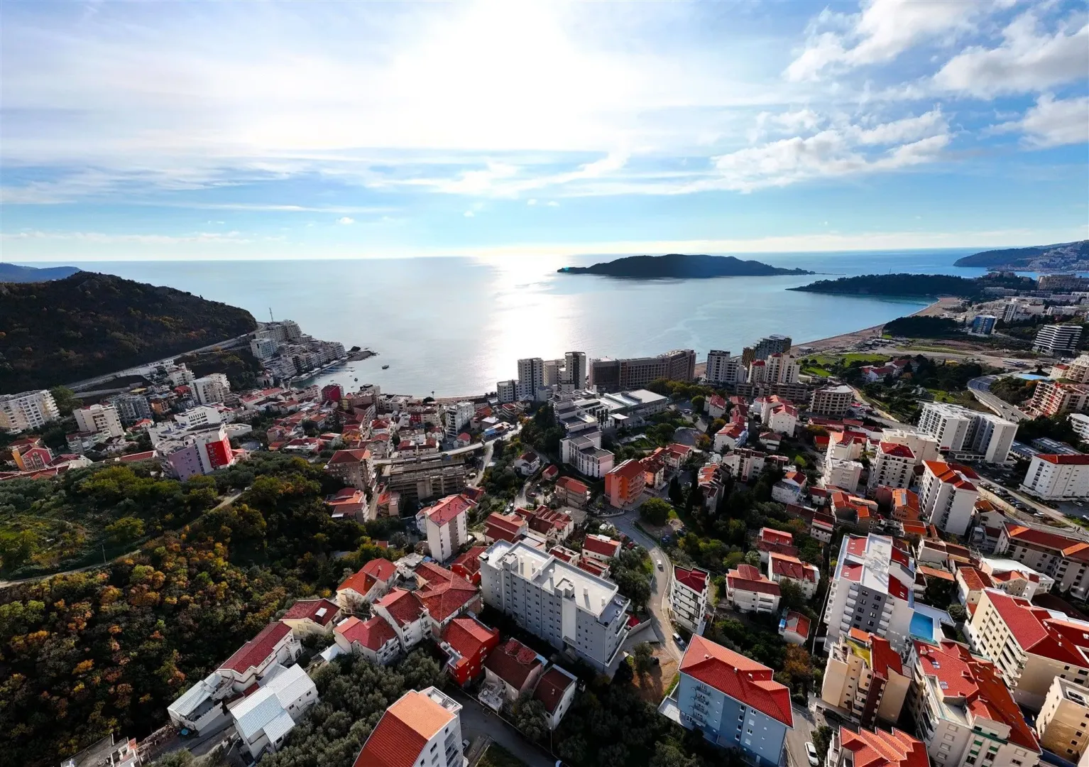 Panoramski pogled iz vazduha na primorski grad i more pod suncem.