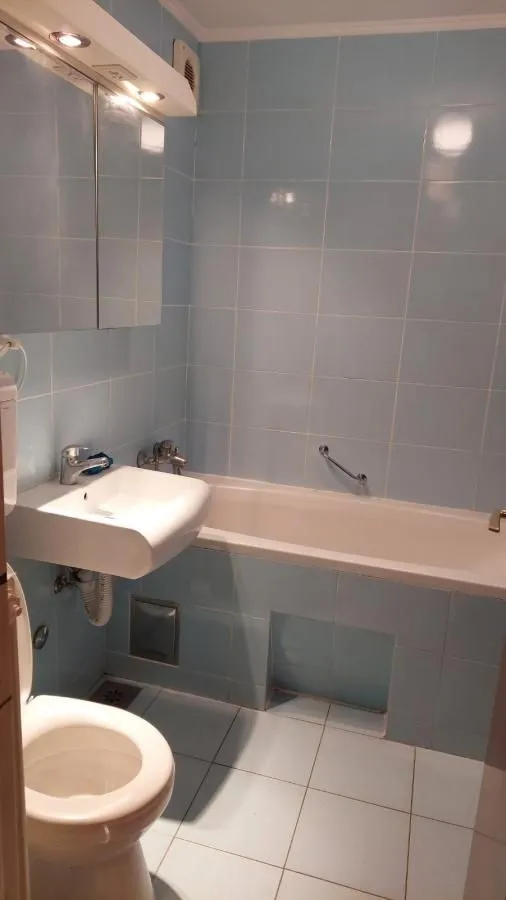 Kupatilo opremljeno kadom, umivaonikom i toaletom, obloženo pločicama plave boje.