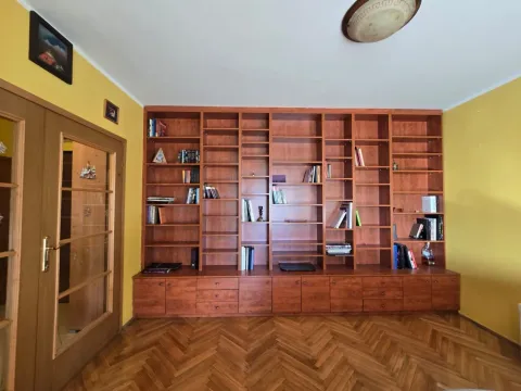 Living room with a large wooden bookshelf and parquet flooring. - image 3