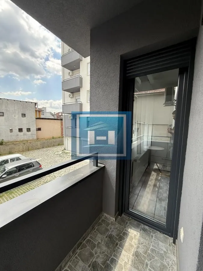 Small tiled balcony with a railing and view of surrounding buildings and parking.