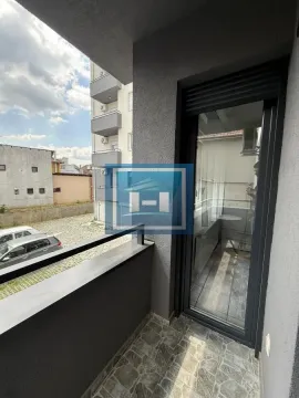 Small tiled balcony with a railing and view of surrounding buildings and parking. - image 8
