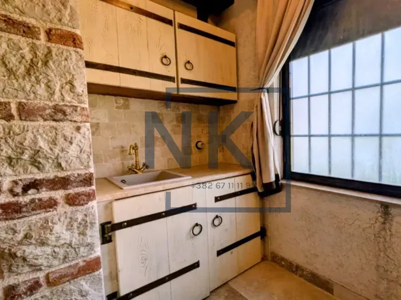 Small kitchen with rustic wooden elements and a stone wall.