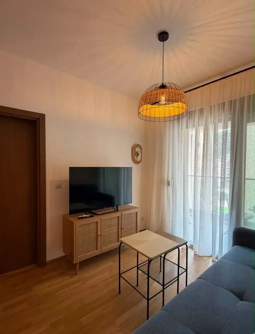 Dnevna soba sa garniturom, televizorom i trpezarijskim stolom.