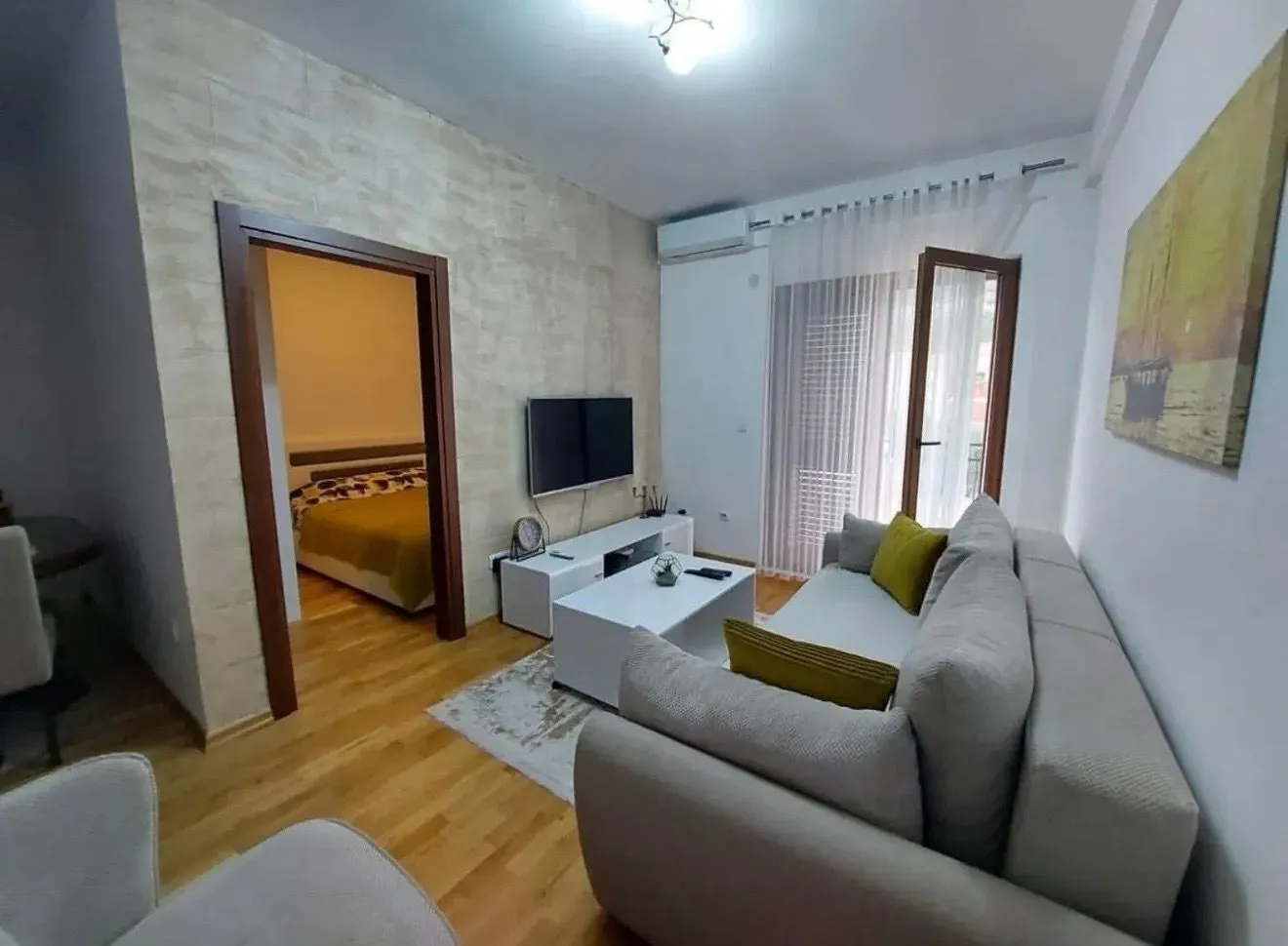 Dnevna soba sa garniturom, TV-om i pogledom na spavaću sobu.