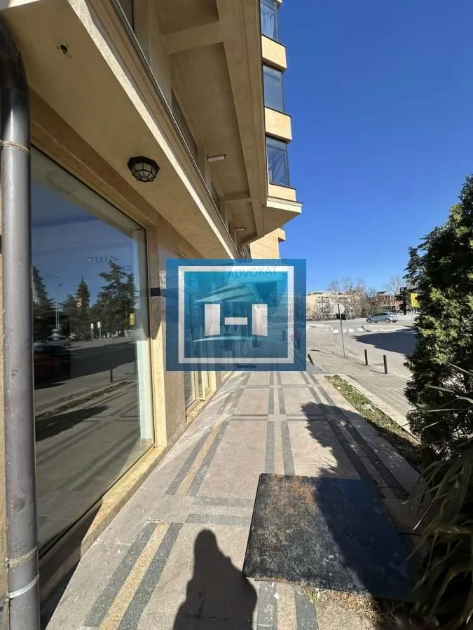 View of the exterior part of the commercial space with a paved walkway in front of large display windows.