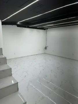 Empty room with white ceramic floor tiles and a black ceiling with linear lighting. - image 5