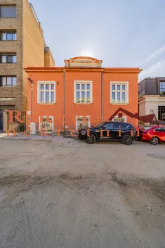 View of the facade of an orange house with parked cars in front. - image 2