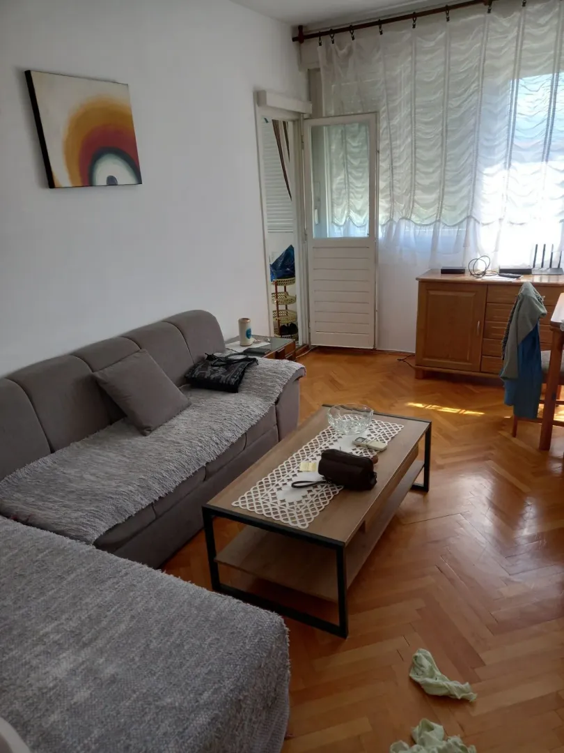 Svijetla dnevna soba sa ugaonom garniturom i drvenim stolom.