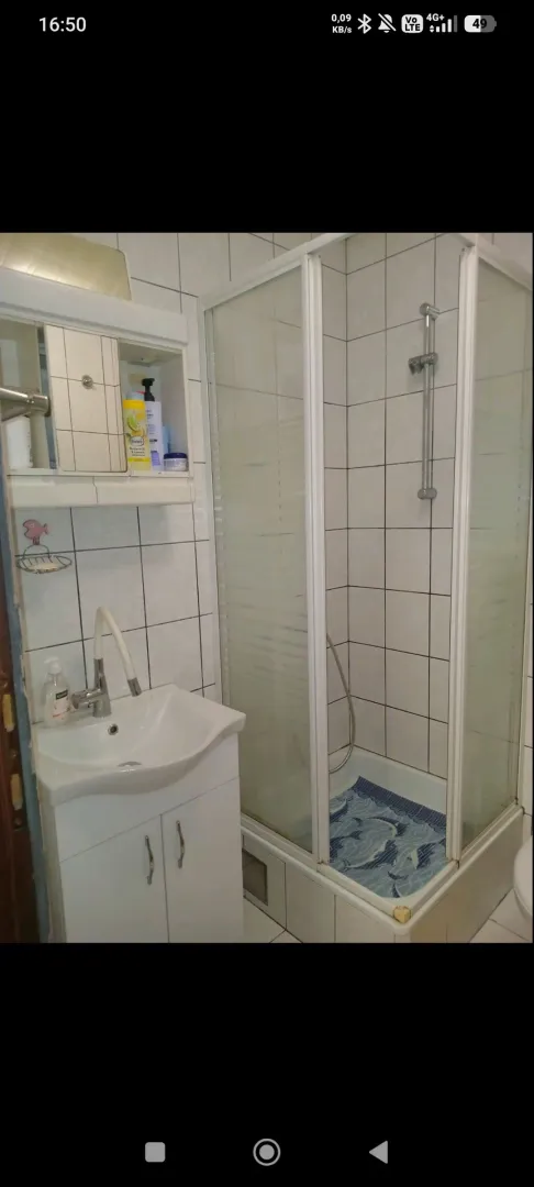 Smaller bathroom with a sink and a shower cabin lined with white tiles.