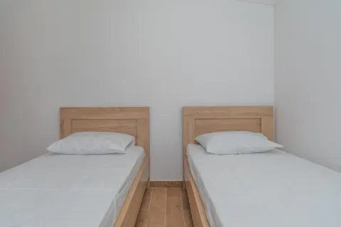 Spavaća soba sa dva drvena kreveta sa bijelom posteljinom. - image 6