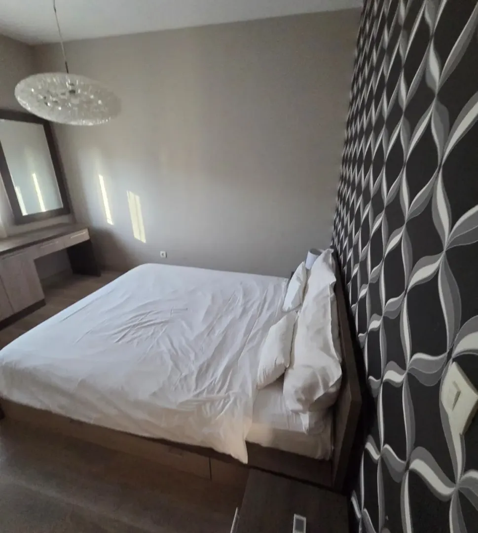 Spacious bedroom with a double bed and decorative wallpaper.