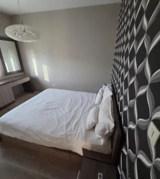 Spacious bedroom with a double bed and decorative wallpaper. - image 7