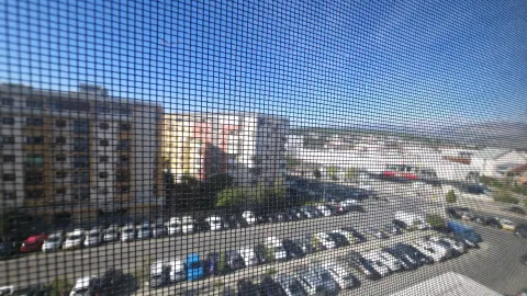 View from the window showing surrounding buildings and parking. - image 7
