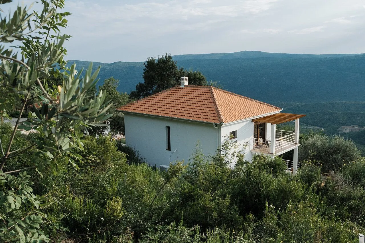 View of the house with a yard and hills in the background.