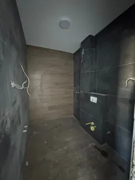 Kupatilo u fazi opremanja sa tamnim pločicama i drvenim zidnim oblogama. - image 6