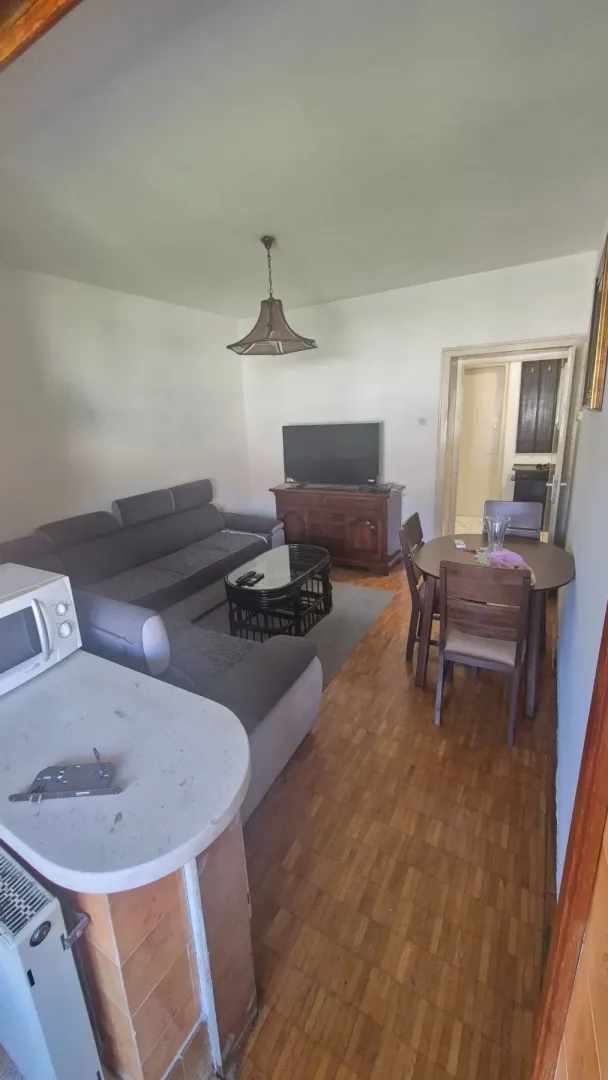 Living room with a sofa, TV, and dining table.