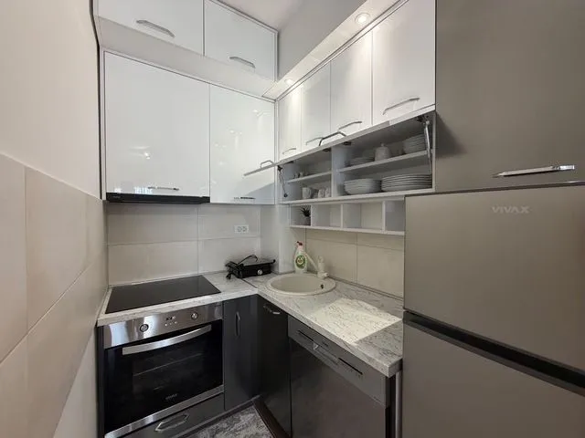 Small modern kitchen with white and dark cabinets and built-in appliances.
