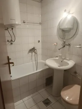 Manje kupatilo sa kadom, umivaonikom, bojlerom i wc šoljom obloženo bijelim pločicama. - image 6