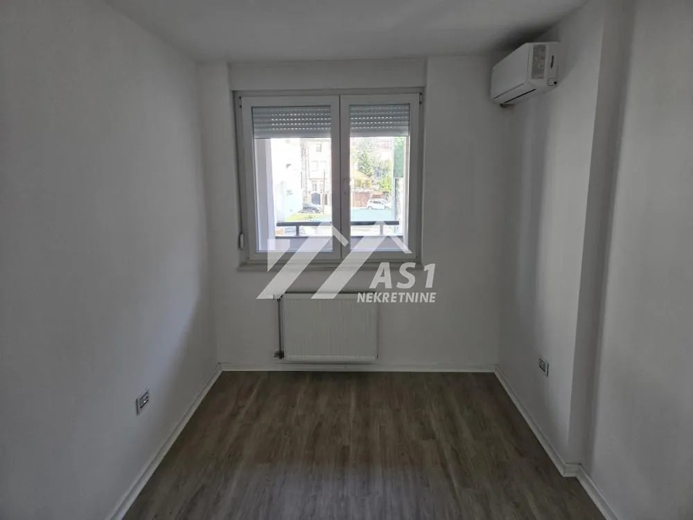 Empty room with a window and an air conditioner.