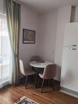 Small dining area with a table and chairs by the window. - image 8