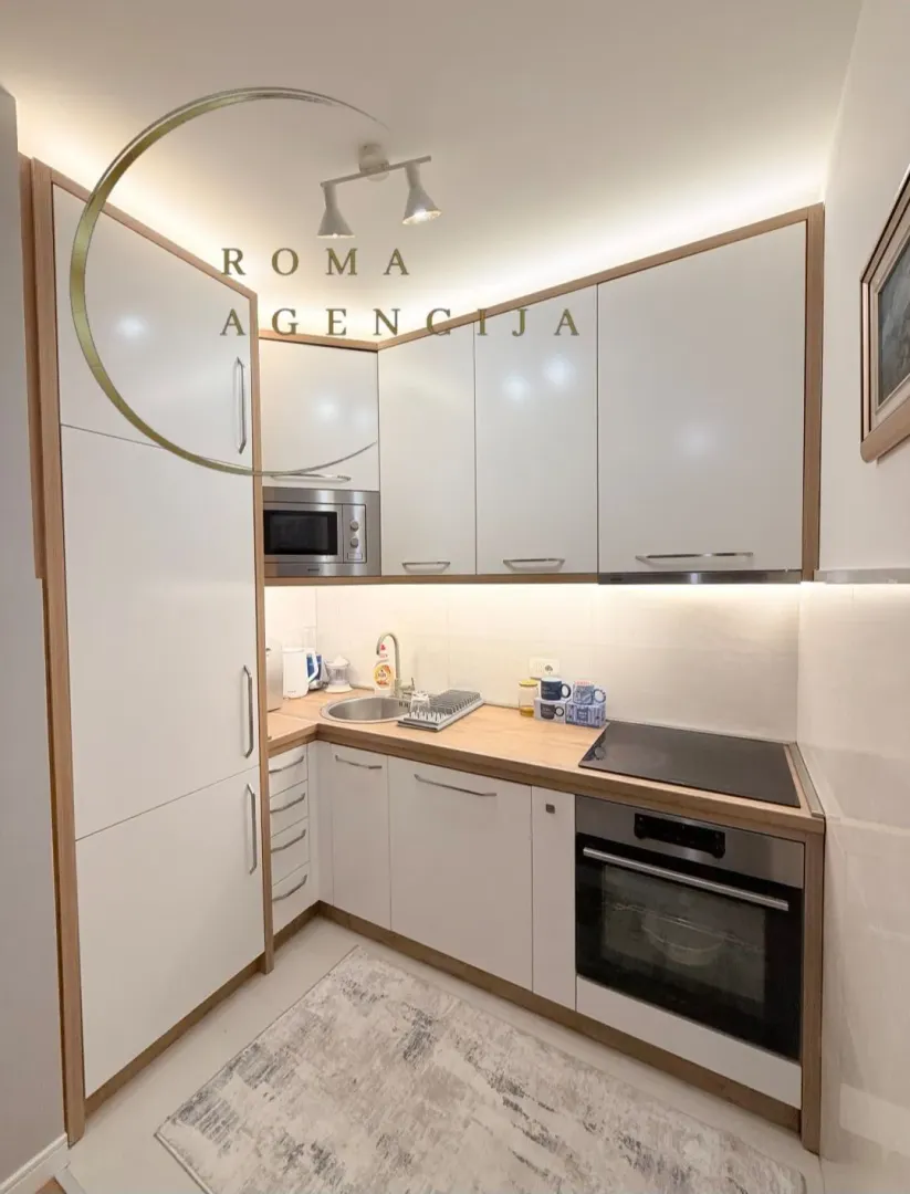 Modern white kitchen with wooden details and built-in appliances.
