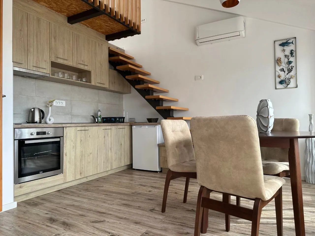 Living room with kitchen and loft stairs.
