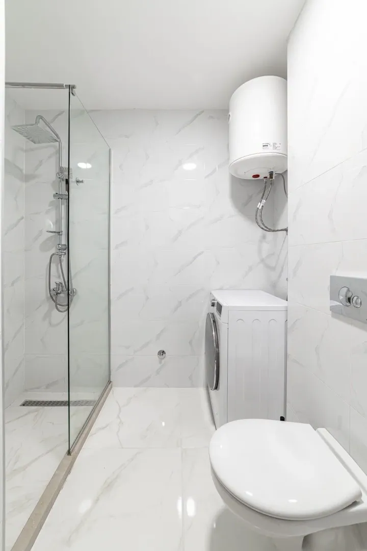 Moderne kupatilo sa tuš kabinom, WC šoljom, veš mašinom i bojlerom.