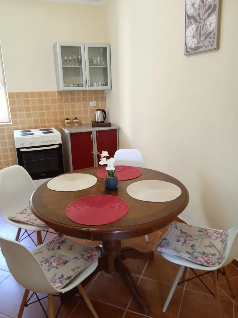 Dining table with chairs and kitchen elements in the background.