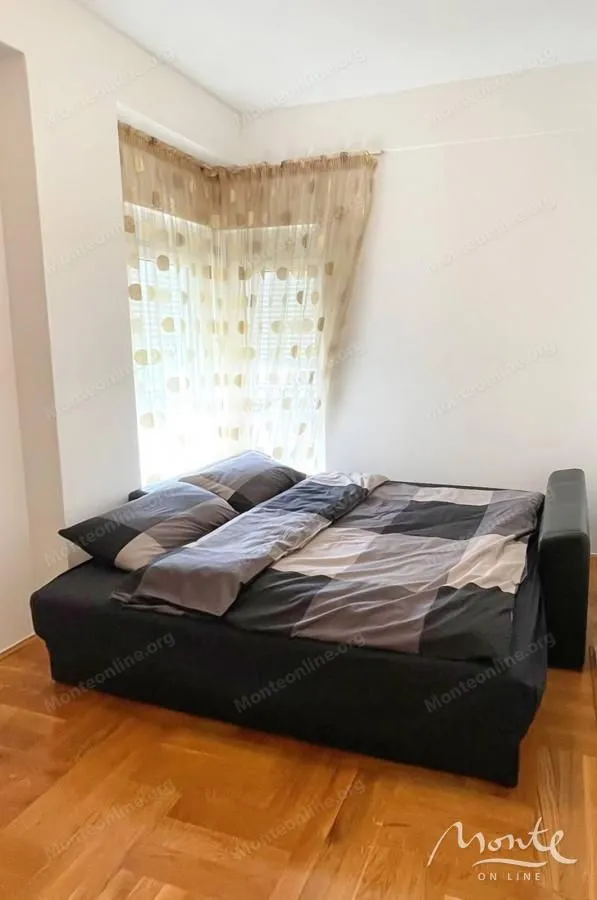 Spavaća soba sa bračnim krevetom i prozorom prekrivenim zavjesama.