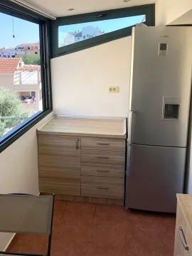 Small kitchen with wood-patterned cabinets and a large refrigerator next to the window. - image 13