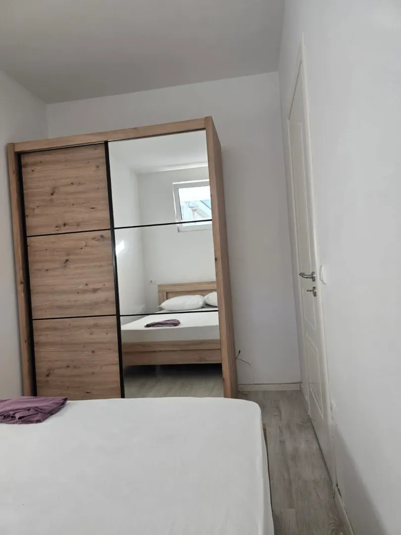 Spavaća soba sa krevetom i velikim ormarom sa ogledalom.