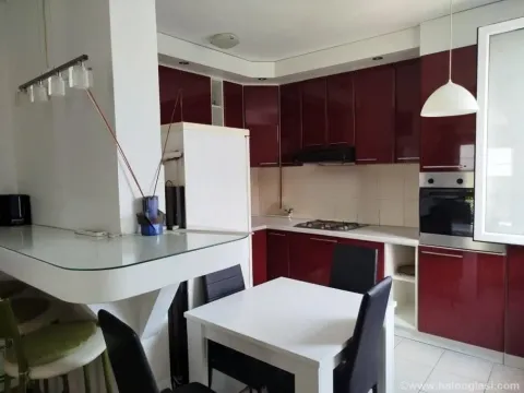 Kuhinja sa trpezarijom opremljena bordoom i belom kuhinjskom garniturom. - image 3