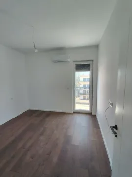 Prazna soba sa drvenim podom, klima uređajem i balkonskim vratima. - image 2