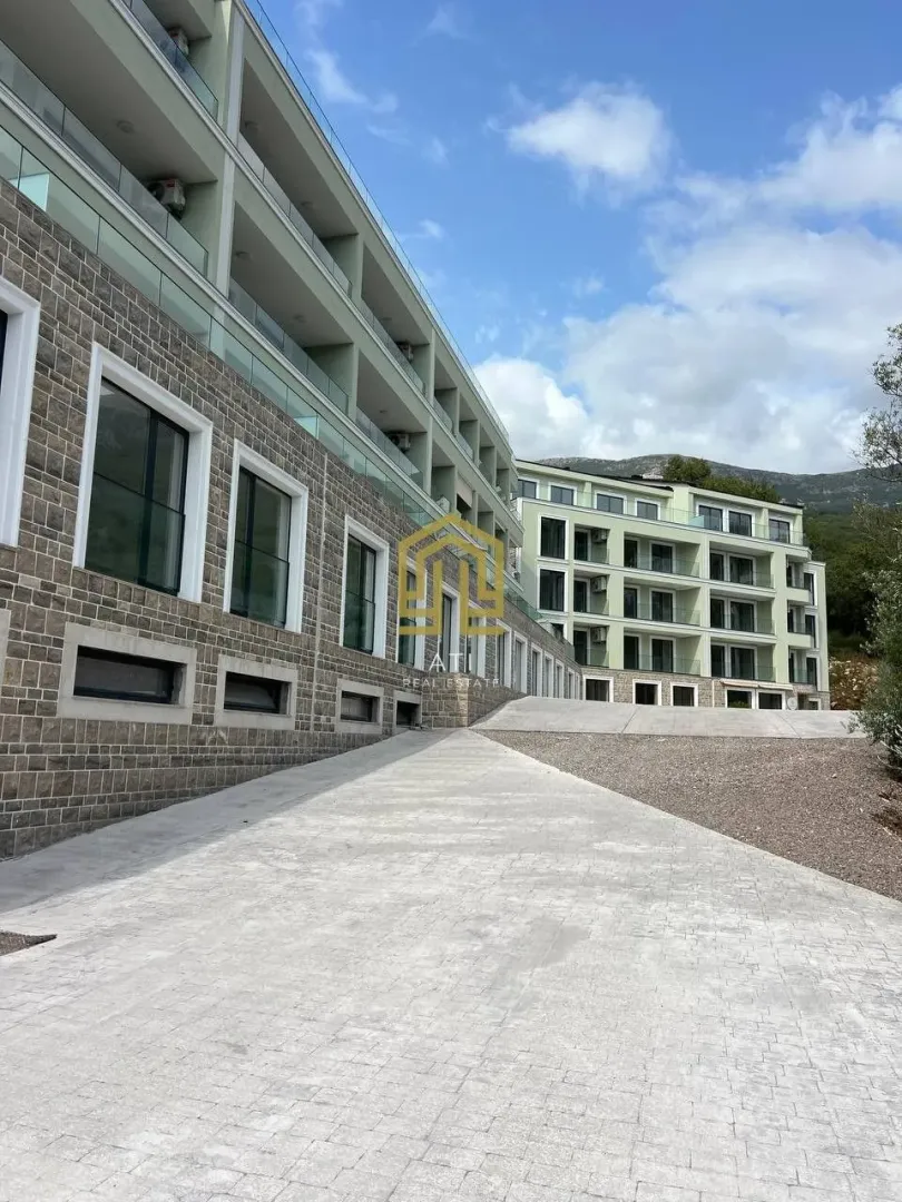 Eksterijer moderne stambene zgrade sa popločanim dvorištem i prilazom.