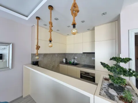Modern kitchen with light cabinetry and distinctive pendant lights hanging on ropes. - image 2
