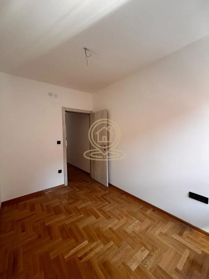 Empty room with parquet flooring and an open door.