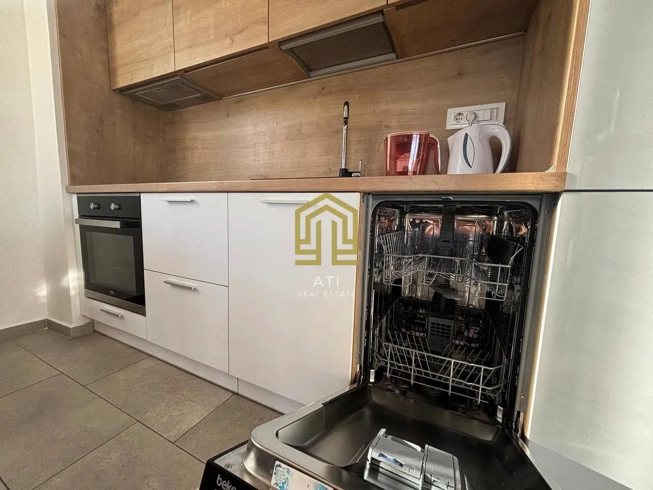 Modern kitchen with white cabinets and wooden details, featuring an open dishwasher.