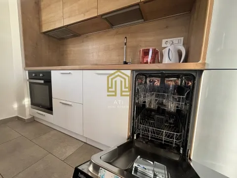 Modern kitchen with white cabinets and wooden details, featuring an open dishwasher. - image 9