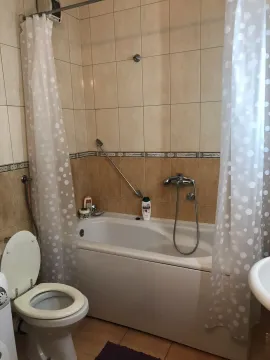 A bathroom with a bathtub, white curtain, and toilet. - image 16