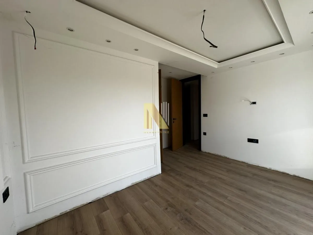 Empty room under construction with installed flooring and decorative wall moldings.