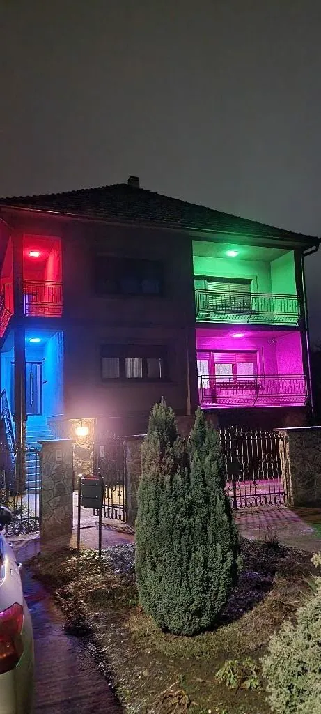 Noćni izgled kuće sa dvorištem i osvetljenjem u boji.