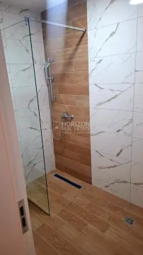 Modern bathroom with a walk-in shower, decorated with wood-effect and marble-effect ceramic tiles. - image 8