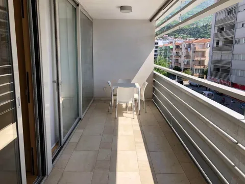 Prostrana natkrivena terasa sa stolom i stolicama i pogledom na grad. - image 3