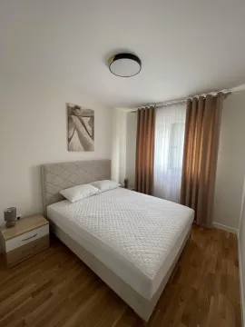 Bedroom with a double bed, bedside tables, and a window with curtains. - image 7
