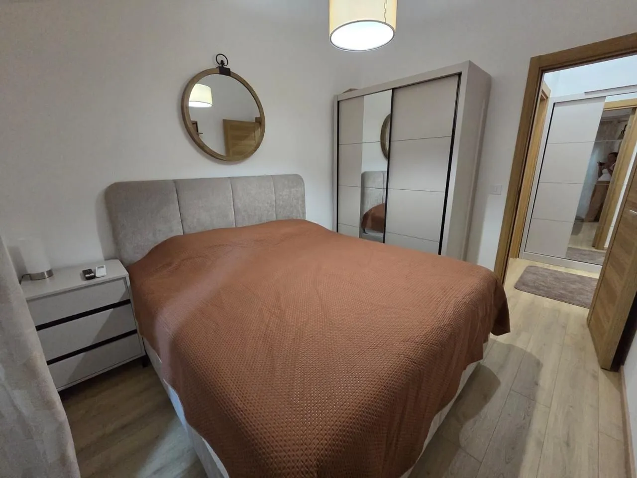 Furnished bedroom with a double bed, wardrobe, and mirror.